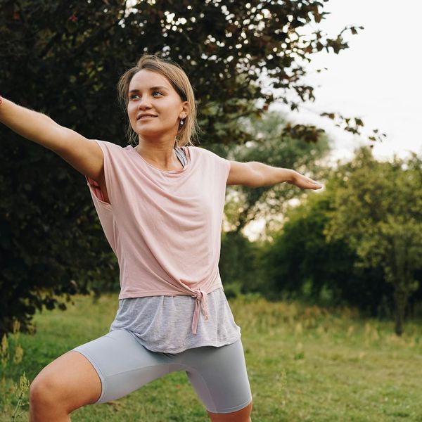 Smiling person stretching outdoors, enjoying the feeling of well-being.